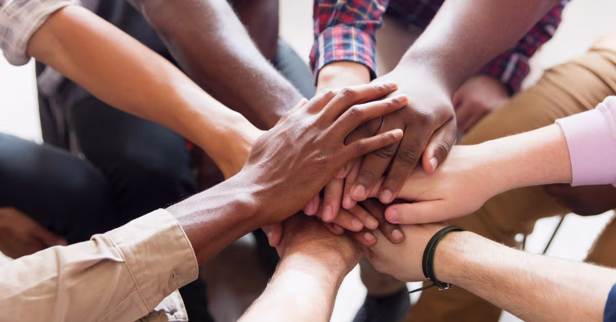 A group of people in a circle with their hands on top of each other