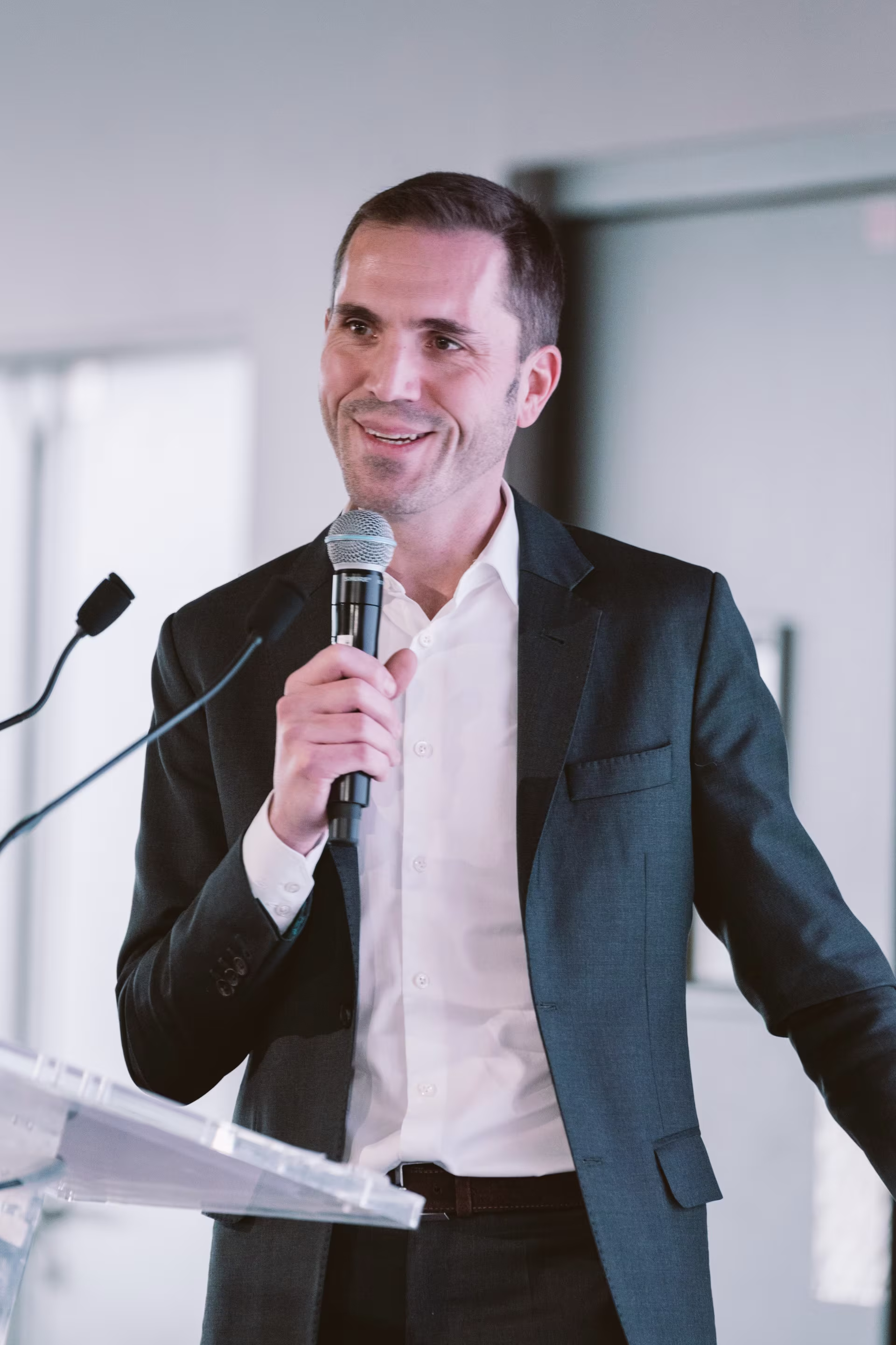 Arnaud Sabadie holding a microphone at a podium.