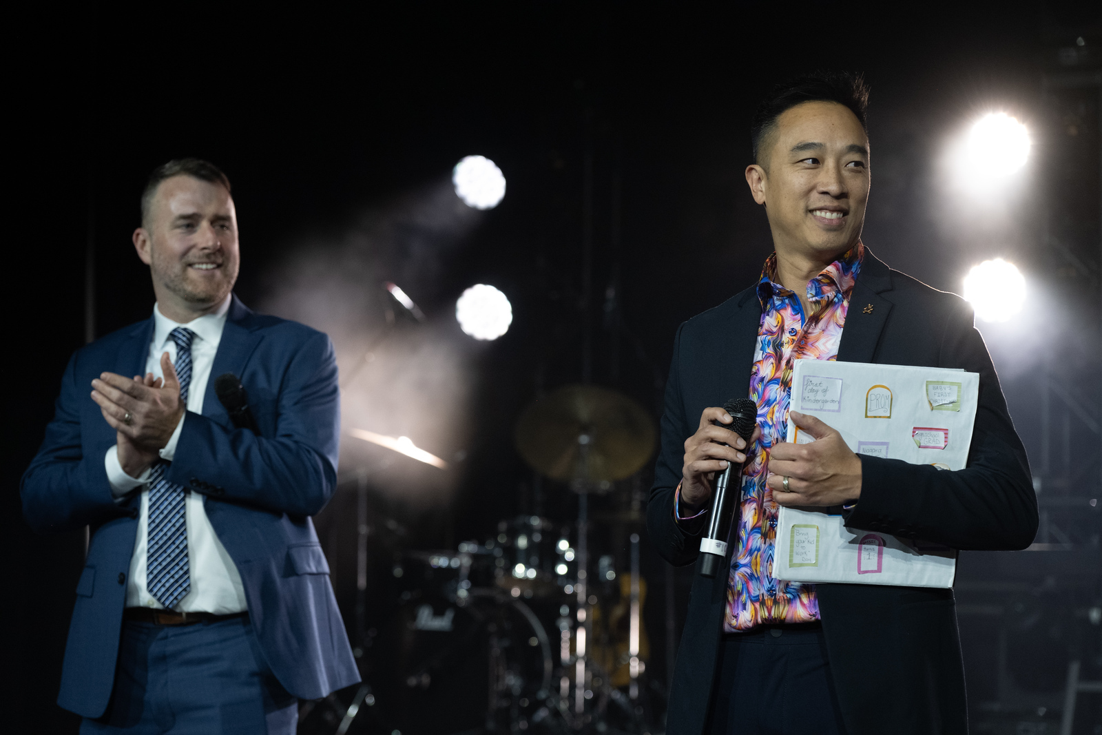 Two men in suits stand on a stage.