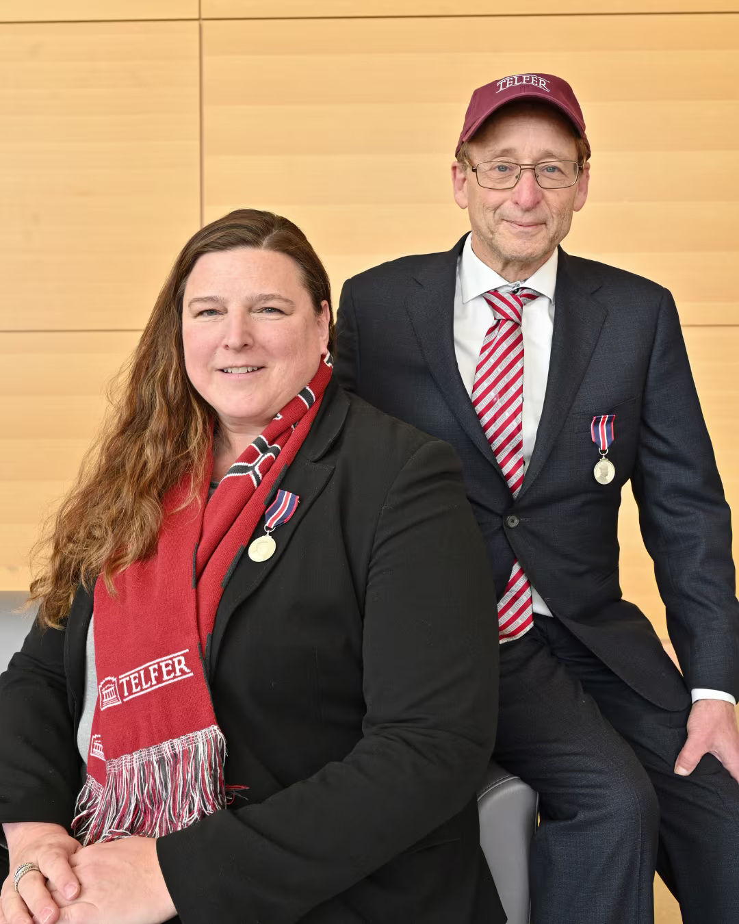 A woman wearing a red scarf and a man in a red baseball cap sit on a couch.