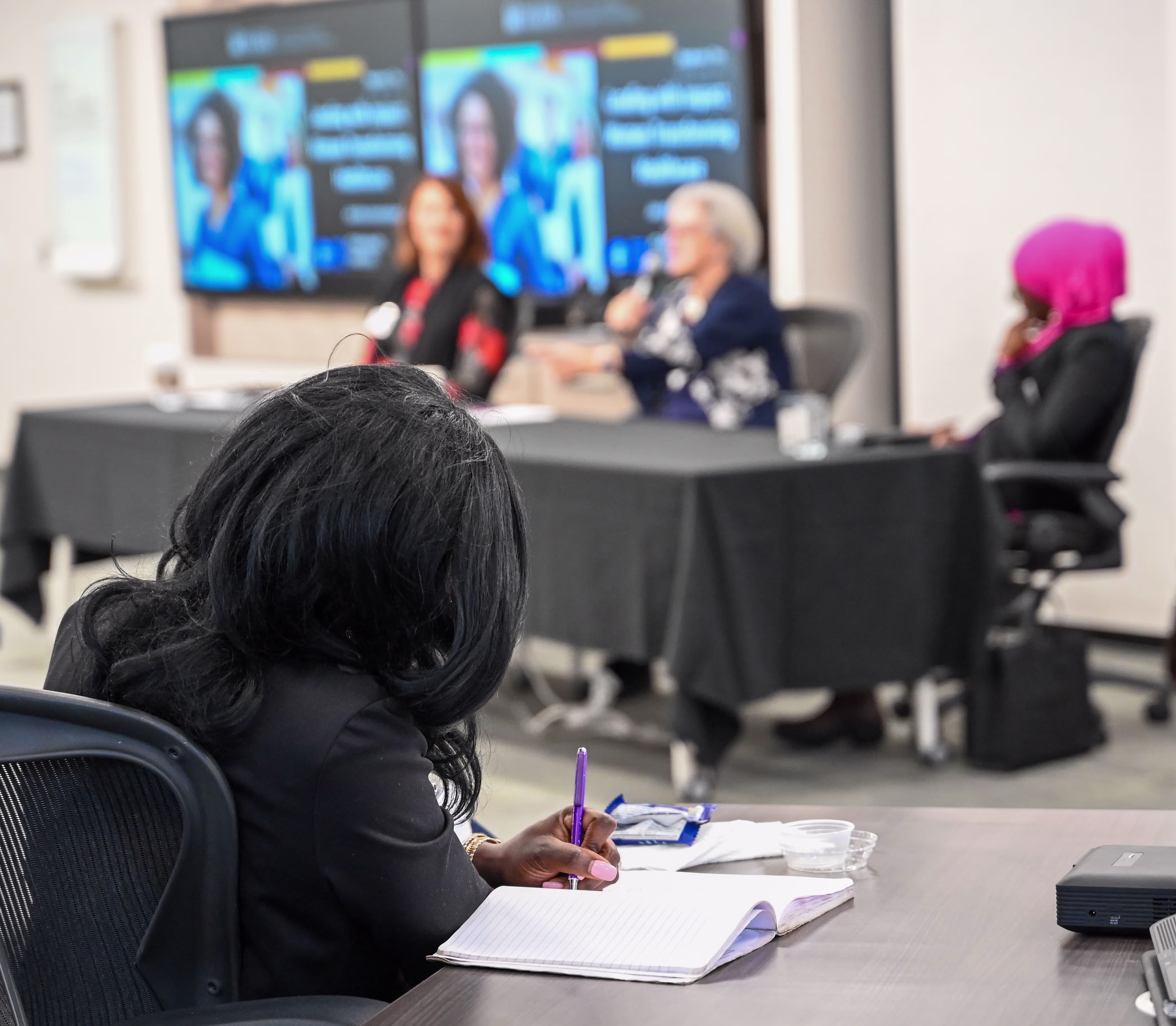 A woman takes notes with a paper and pen while listening to the panel discussion at Telfer’s Executive Campus on March 5, 2025.