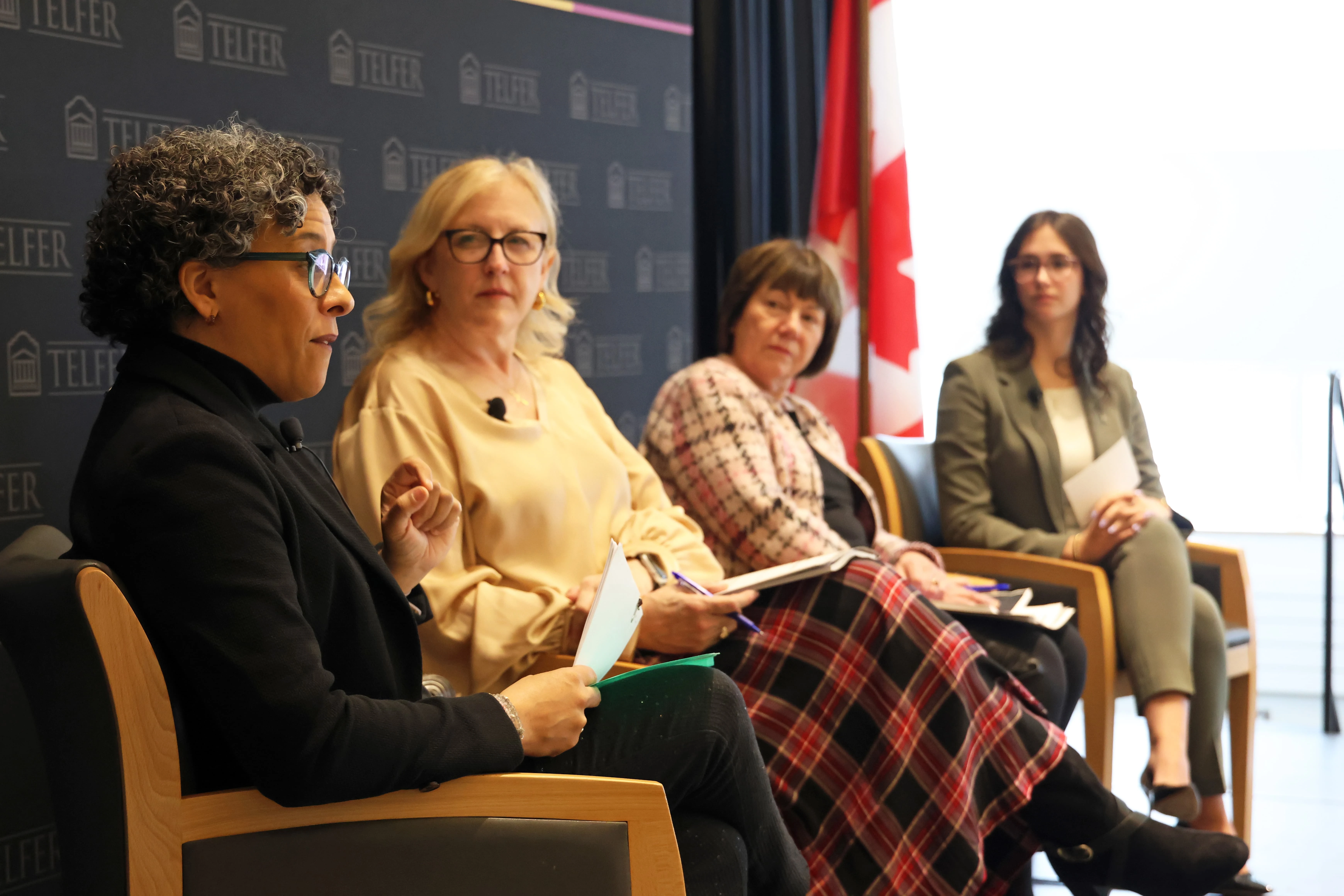 Four women sitting in chairs with a telfer backdrop