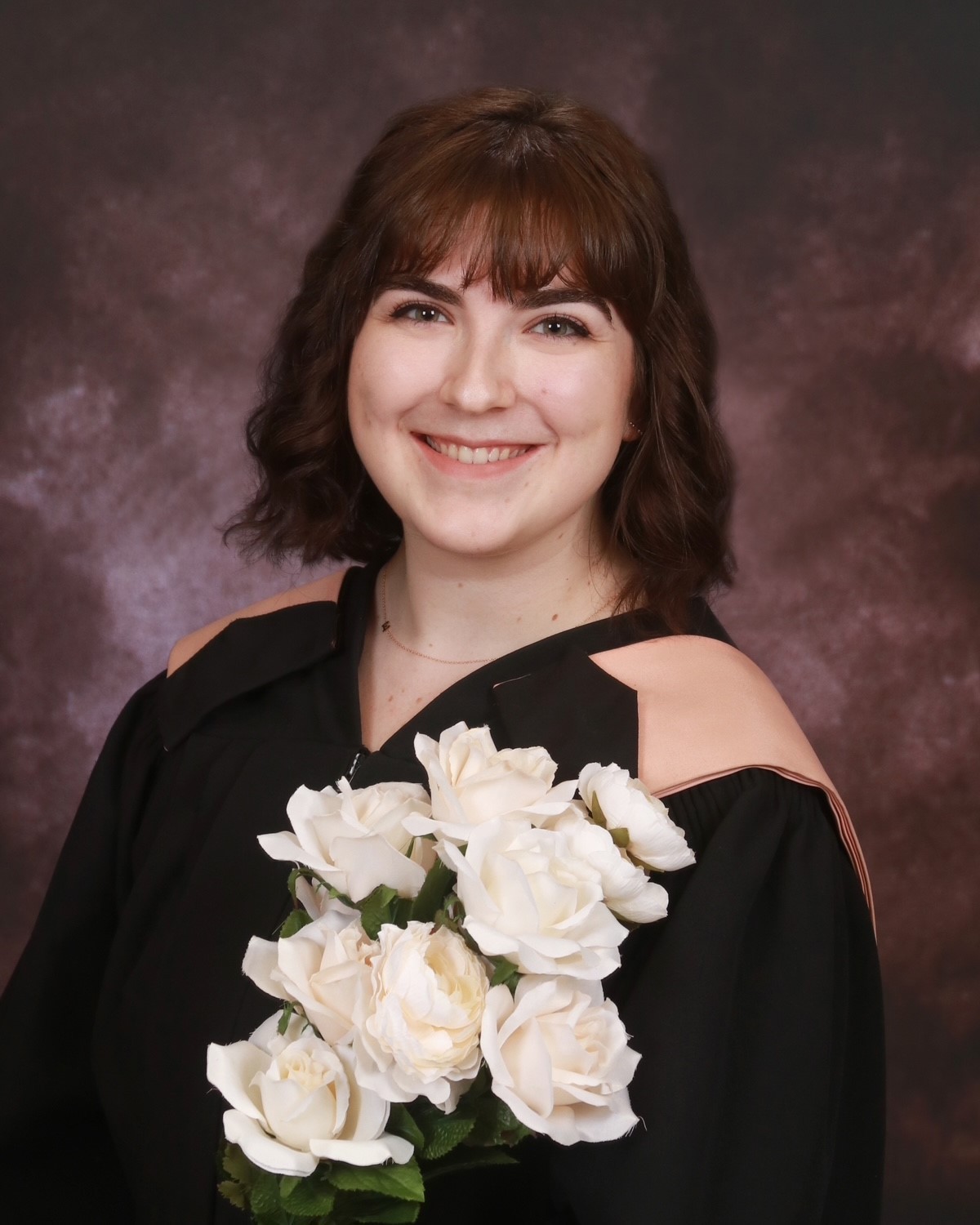 Portrait de fin d’études d’une jeune femme tenant un bouquet de fleurs blanches
