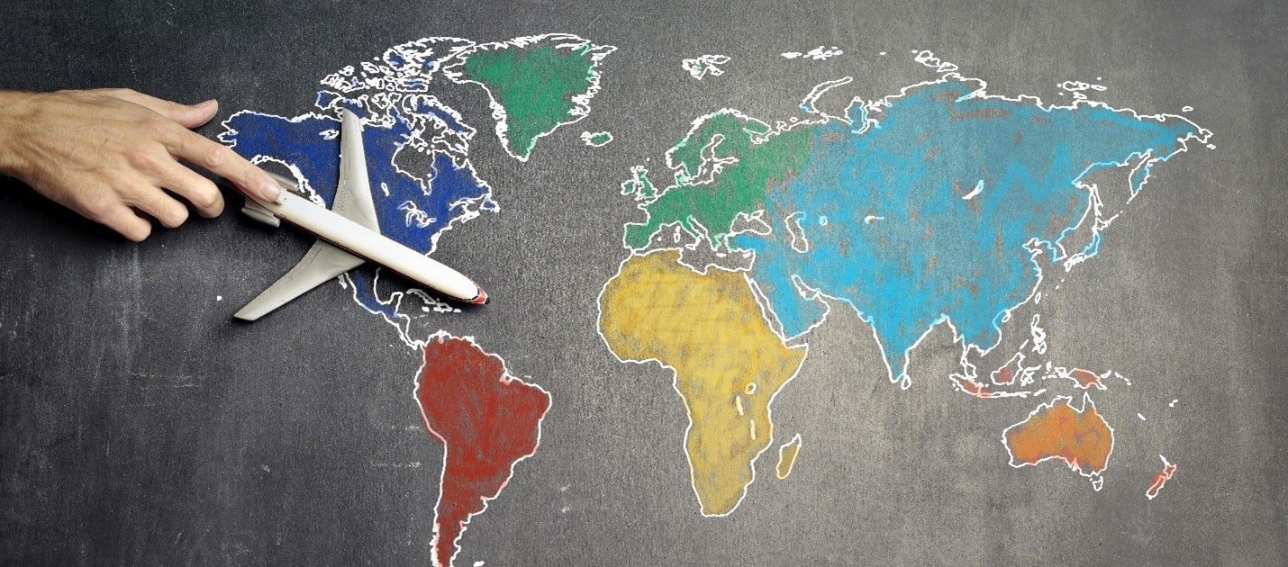 Map of the world on a chalk board with person pushing a toy airplane over North America