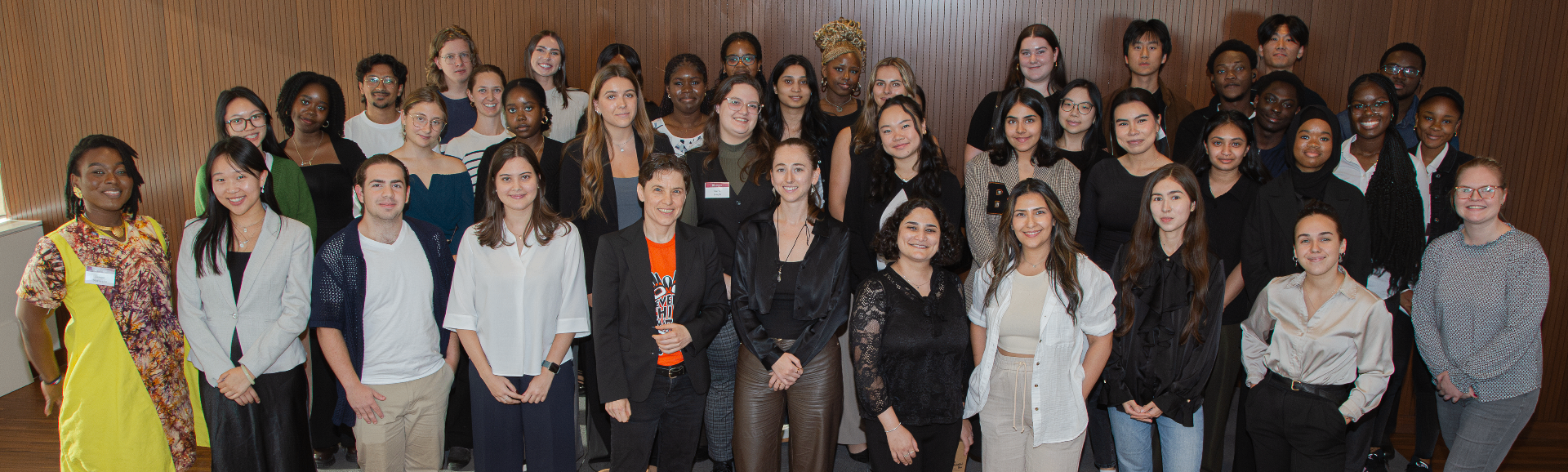 Un grand groupe diversifié d’étudiantes, d’étudiants et d’organisateurs pose ensemble en souriant devant un mur en bois. La photo illustre les participantes et participants du tout premier Sprint d’innovation de Telfer, symbolisant la collaboration, la diversité et l’esprit de communauté.