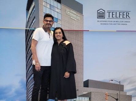 Sunita Sekhon, in her graduation gown, standing with a companion in front of the Telfer School of Management building at the University of Ottawa during her Executive MHA convocation.