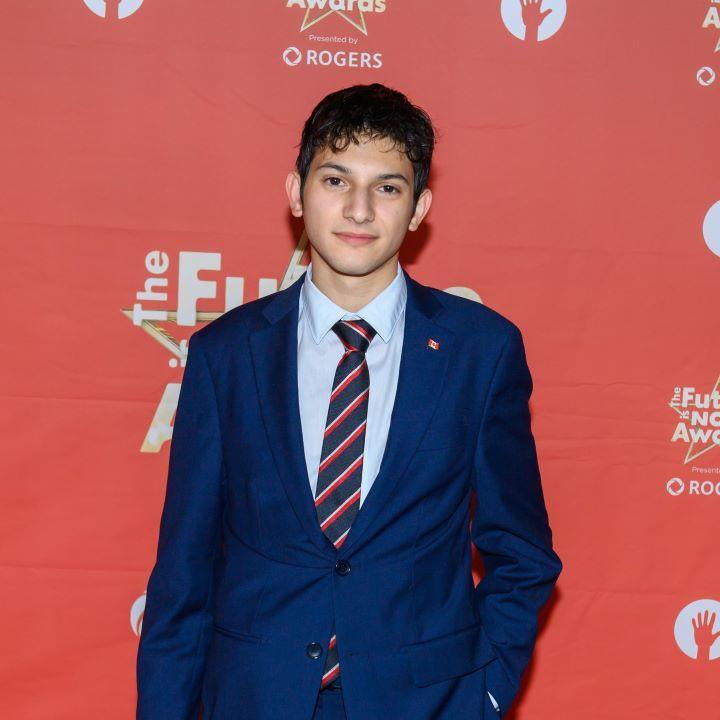 Santiago Proteau-Sanchez posing in front of a red background at The future is now award