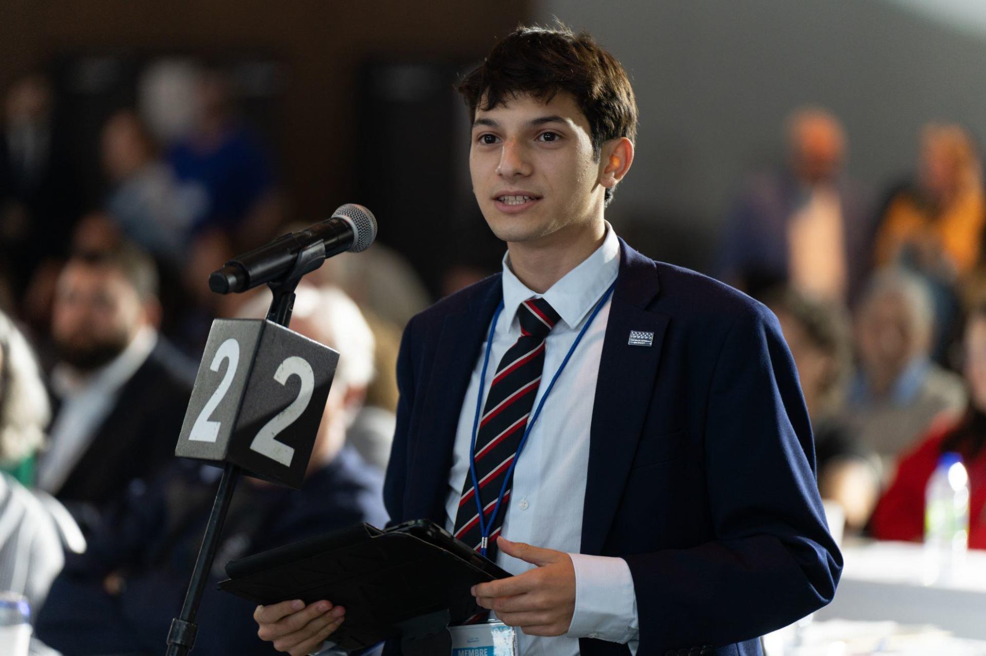 Santiago Proteau-Sanchez speaking in front of a mic