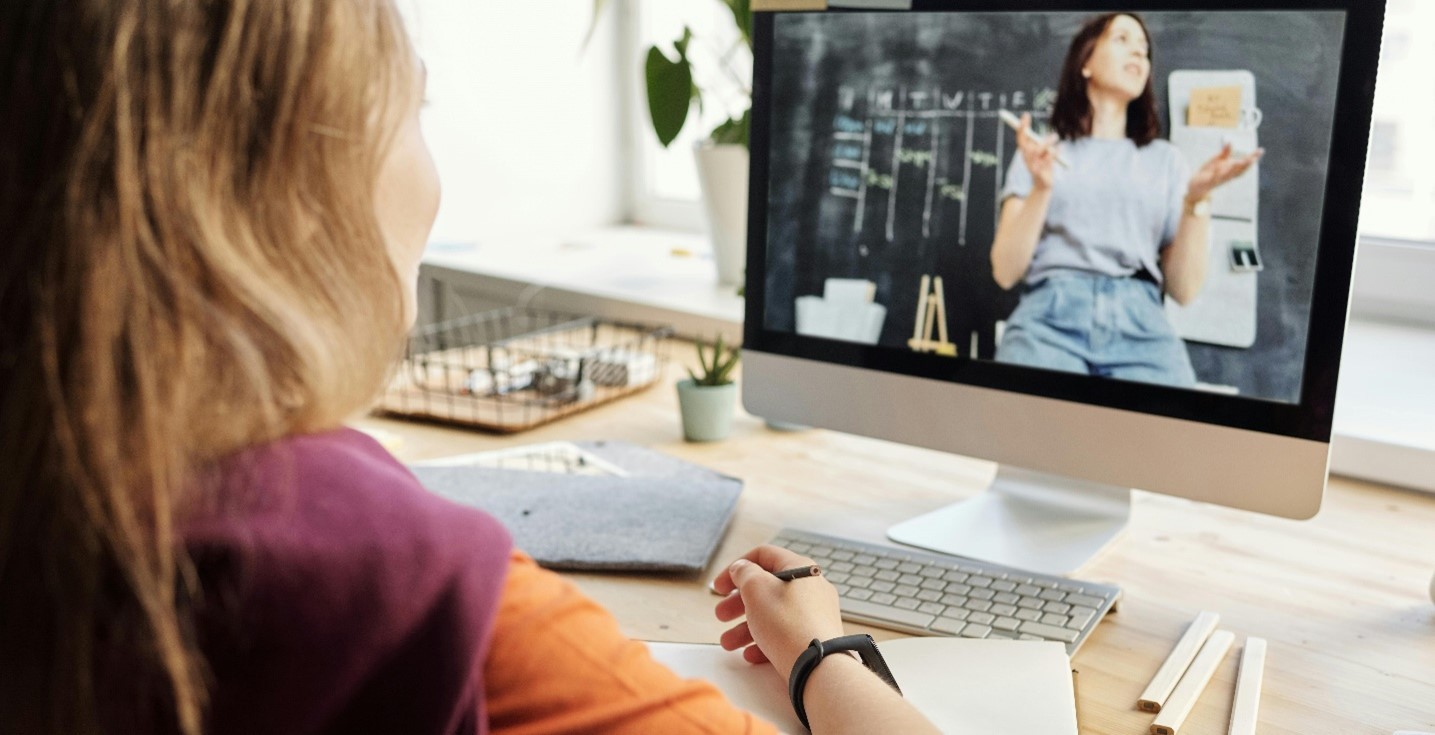 woman seated at a desk taking part in an online class on her laptop