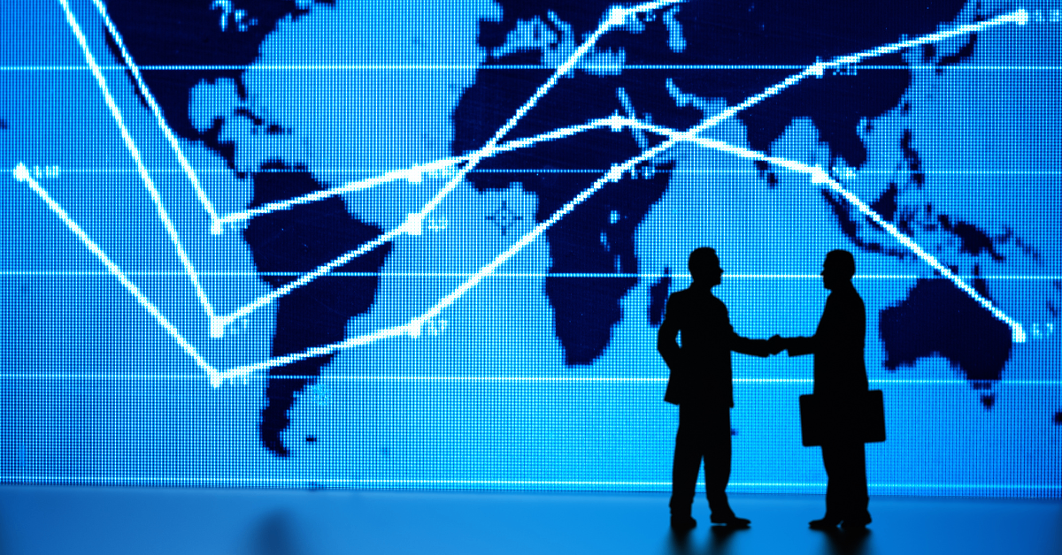 Two people shaking hands in front of a global market graph
