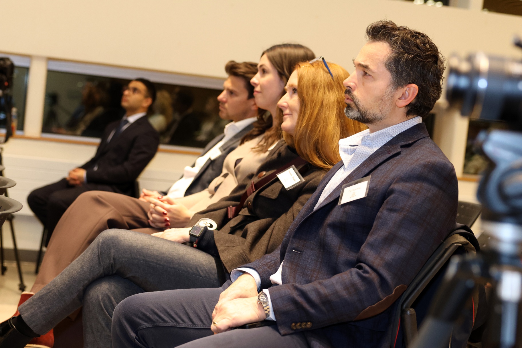 A side view of four attendees sitting in a row, listening to the discussion during the fireside chat