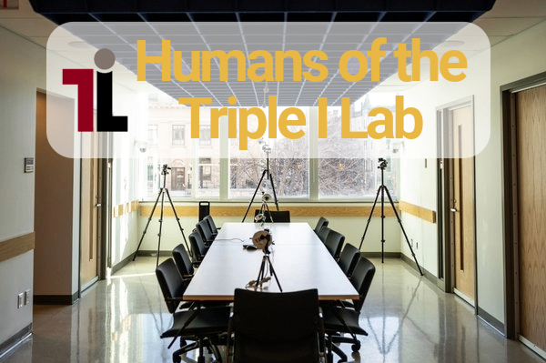 A boardroom with a large table and twelve chairs. A large yellow text that reads “Humans of the Triple I Lab” appears at the top center, and the Triple I Lab logo is to the left of the text.