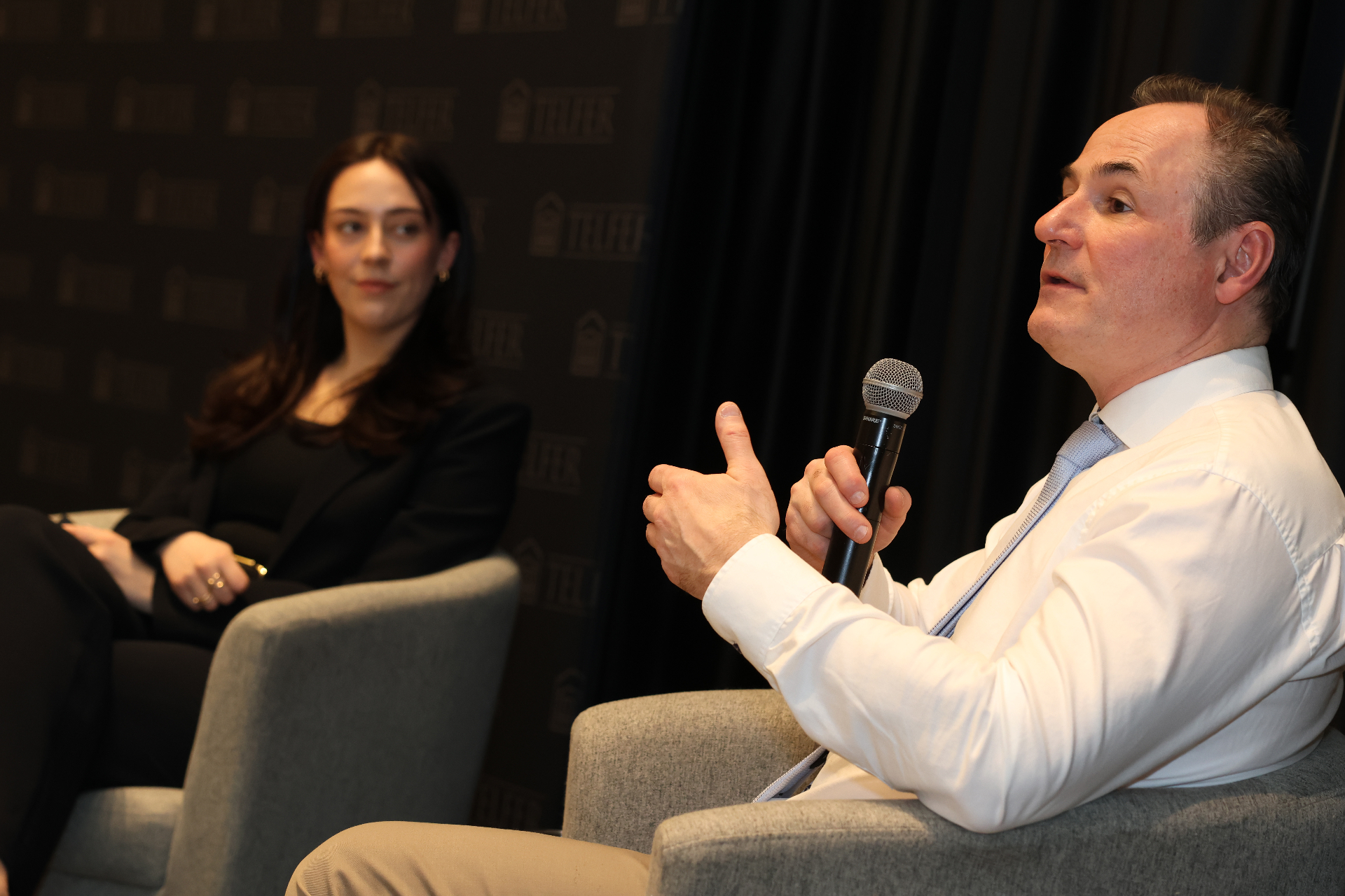 Paul Halucha, sous-ministre de Logement, Infrastructures et Collectivités Canada, vêtu d’une chemise blanche et d’une cravate, parle au micro pendant la causerie aux côtés de la modératrice Alexia Dumouchel