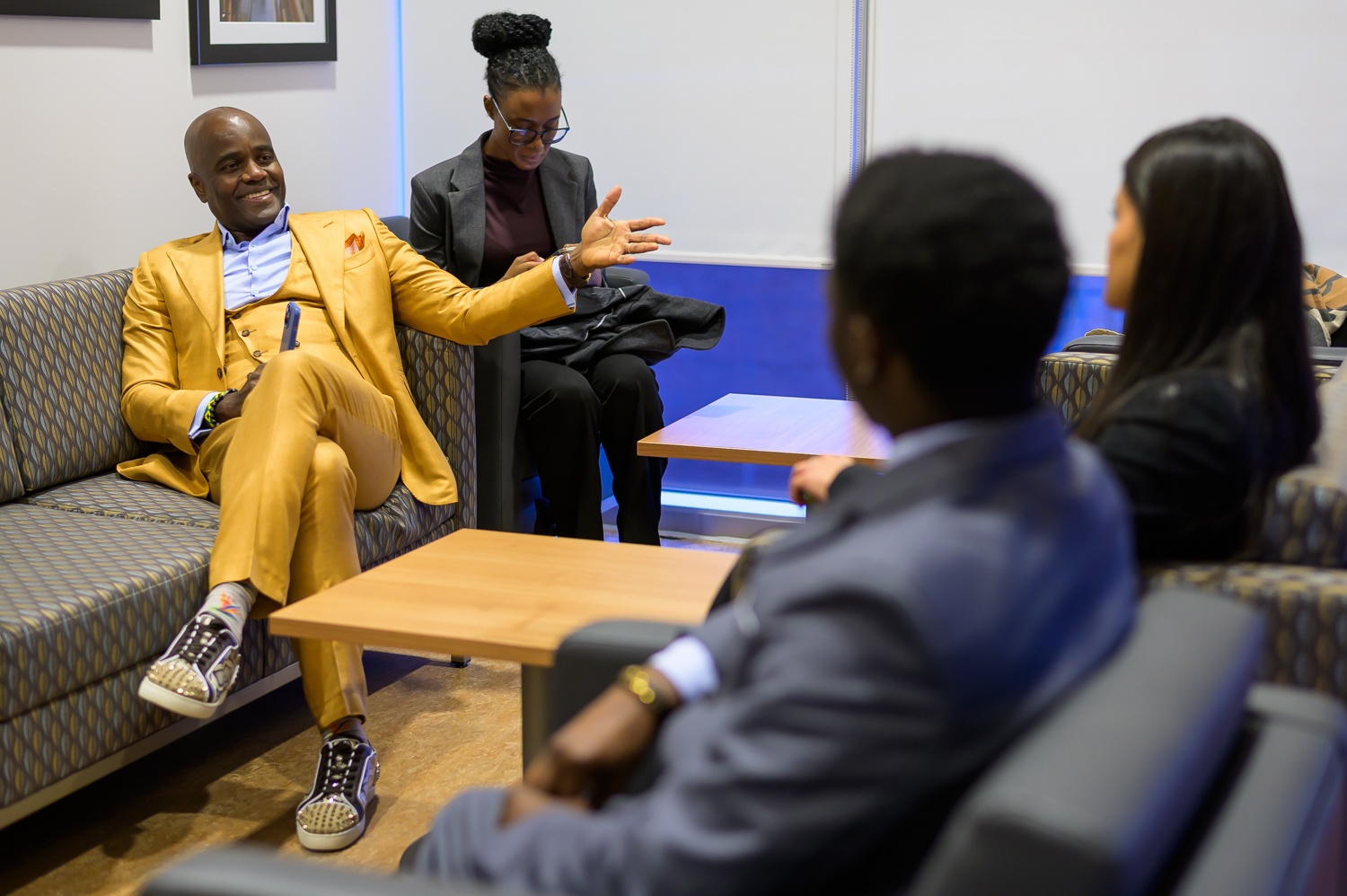 Assis sur un canapé, Wes Hall sourit, en pleine conversation avec Abigail et Louis, boursière et boursier, assis en face de lui