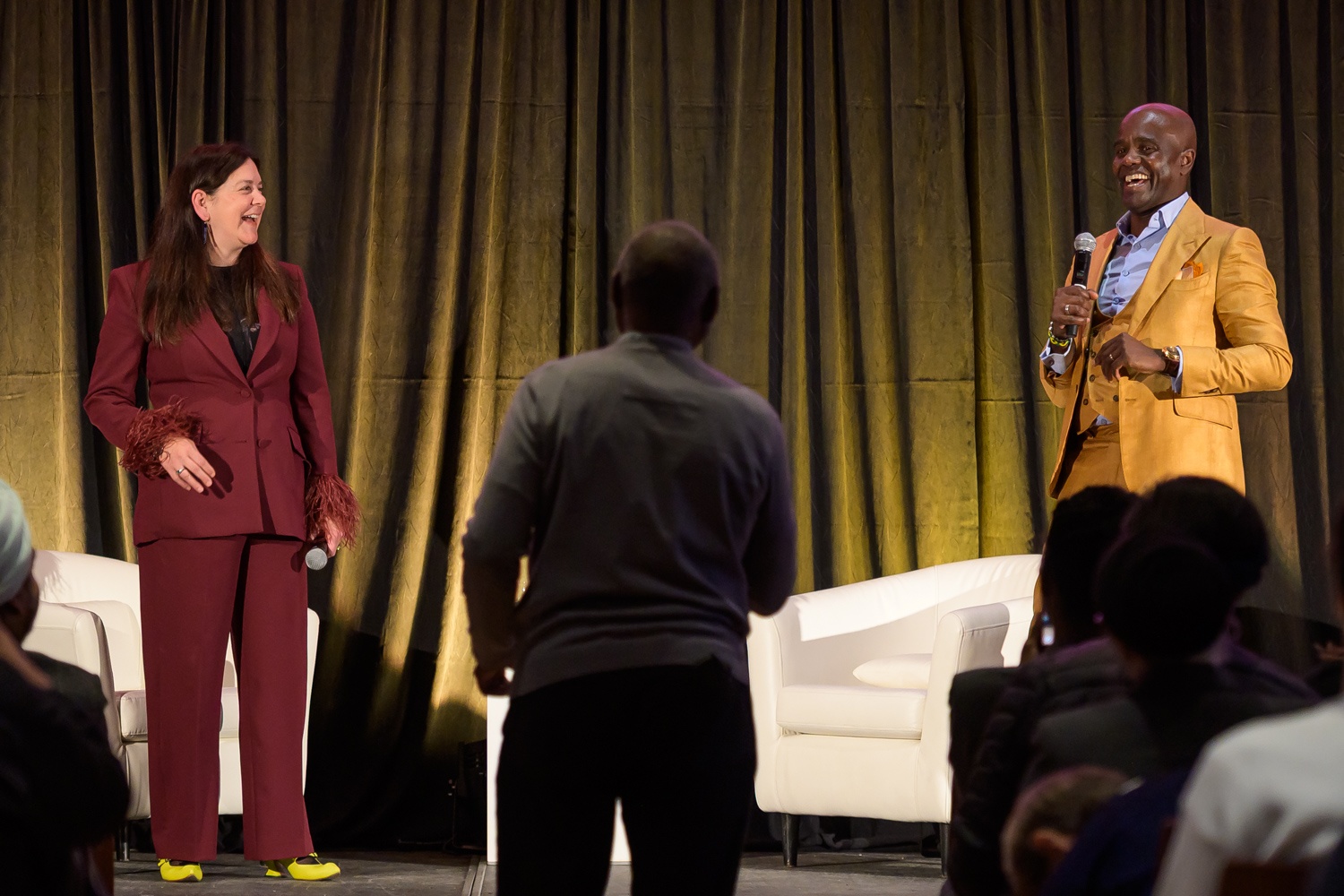 Michelle O’Bonsawin sourit sur scène tandis que Wes Hall répond à une question de l’auditoire