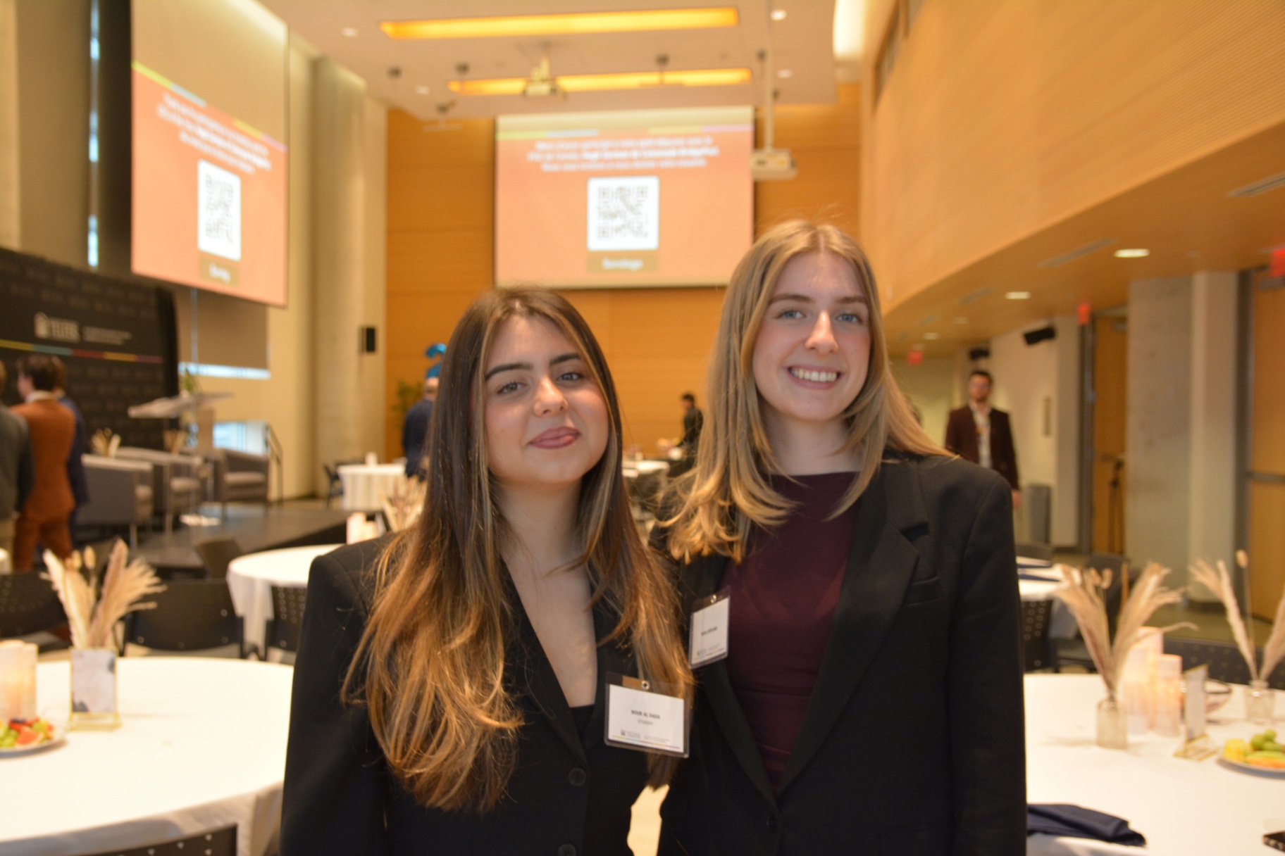 Nour Al Dada et Maya Coopland, en tailleurs noirs, souriant &agrave; l&rsquo;objectif.