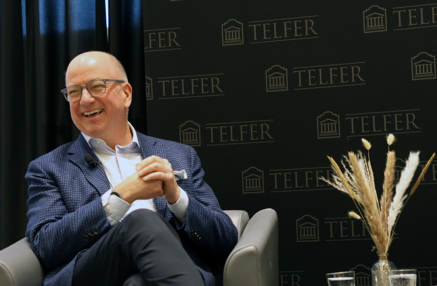 Hugh Gorman, PDG de Colonnade BridgePort et PDG de l’année 2025, sourit à l’auditoire pendant une causerie, en complet bleu devant un arrière-plan aux couleurs de l’École de gestion Telfer.