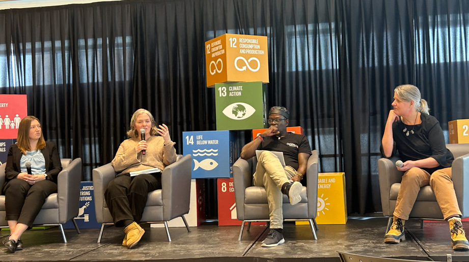 Panelists in discussion during the Innovation Sprint kickoff, seated on stage in front of SDG displays.