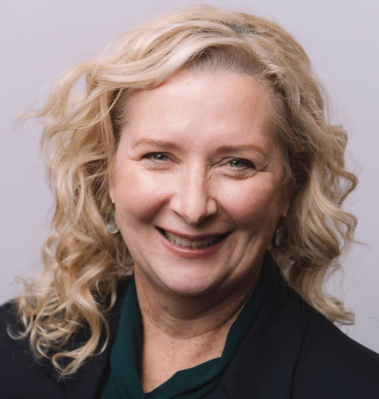 Portrait de Sarah Downey, une femme aux cheveux blonds en train de sourire.