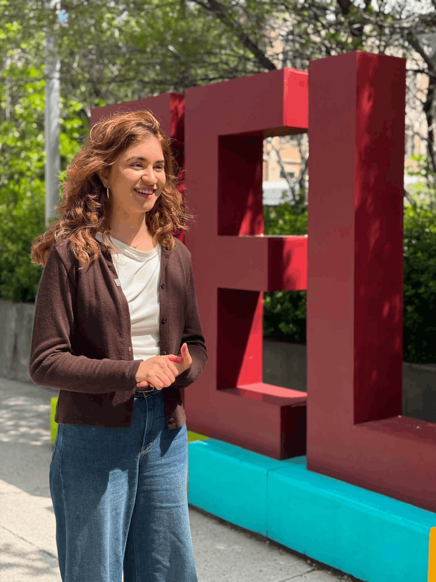 Amanda Maria Kutenski, valedictorian and Master of Science in Health Systems graduate, standing in front of the Telfer School of Management sign on the University of Ottawa campus.