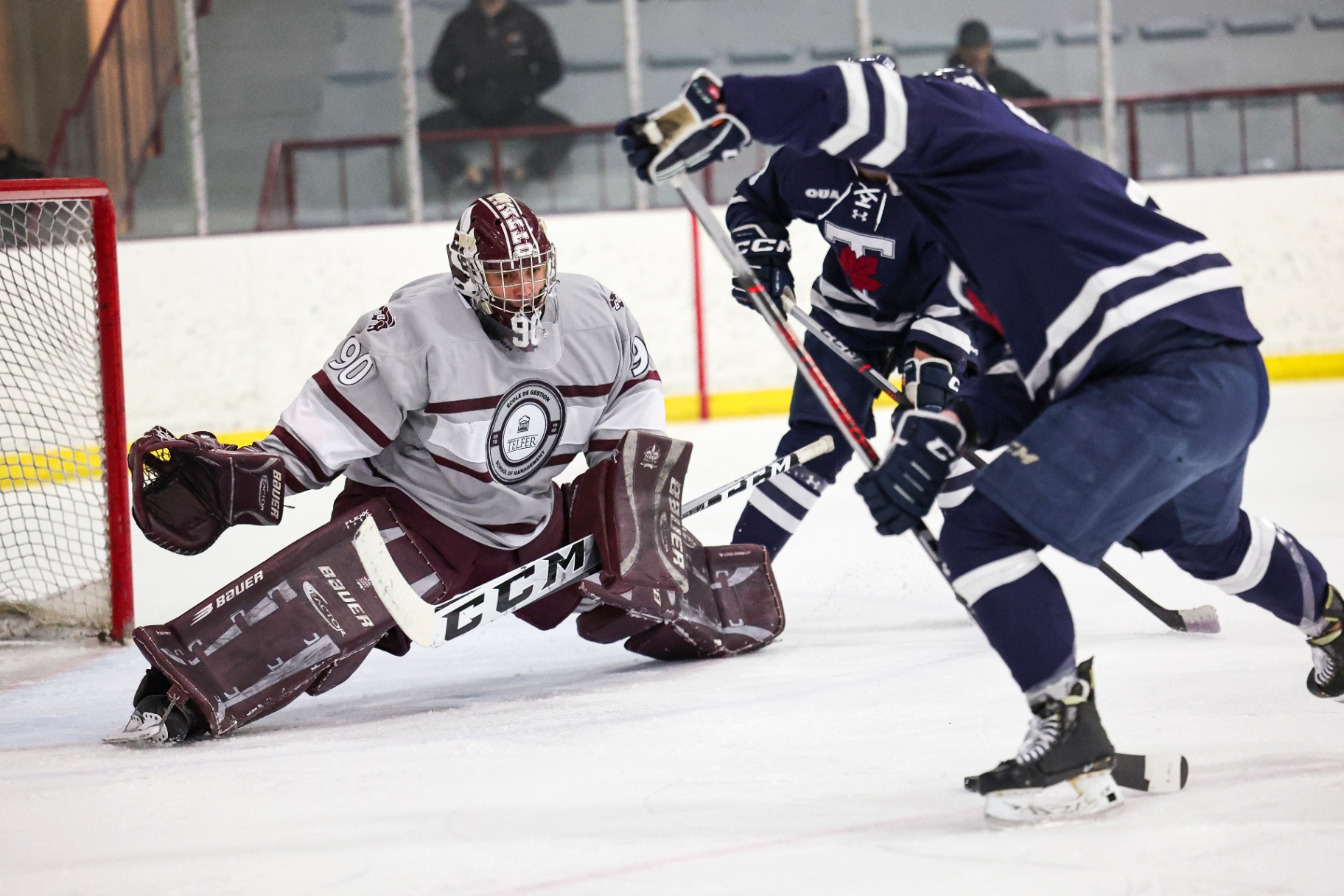 Franky Lapenna crouches low on the ice with his pads spread wide, ready to block a shot against a University of Toronto player.