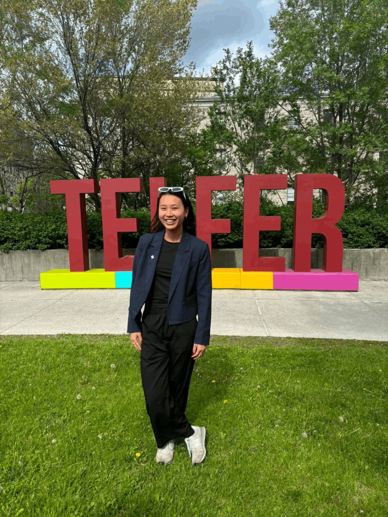 Megan Thompson, valedictorian and Bachelor of Commerce graduate in Marketing, standing in front of the Telfer School of Management sign on the University of Ottawa campus.