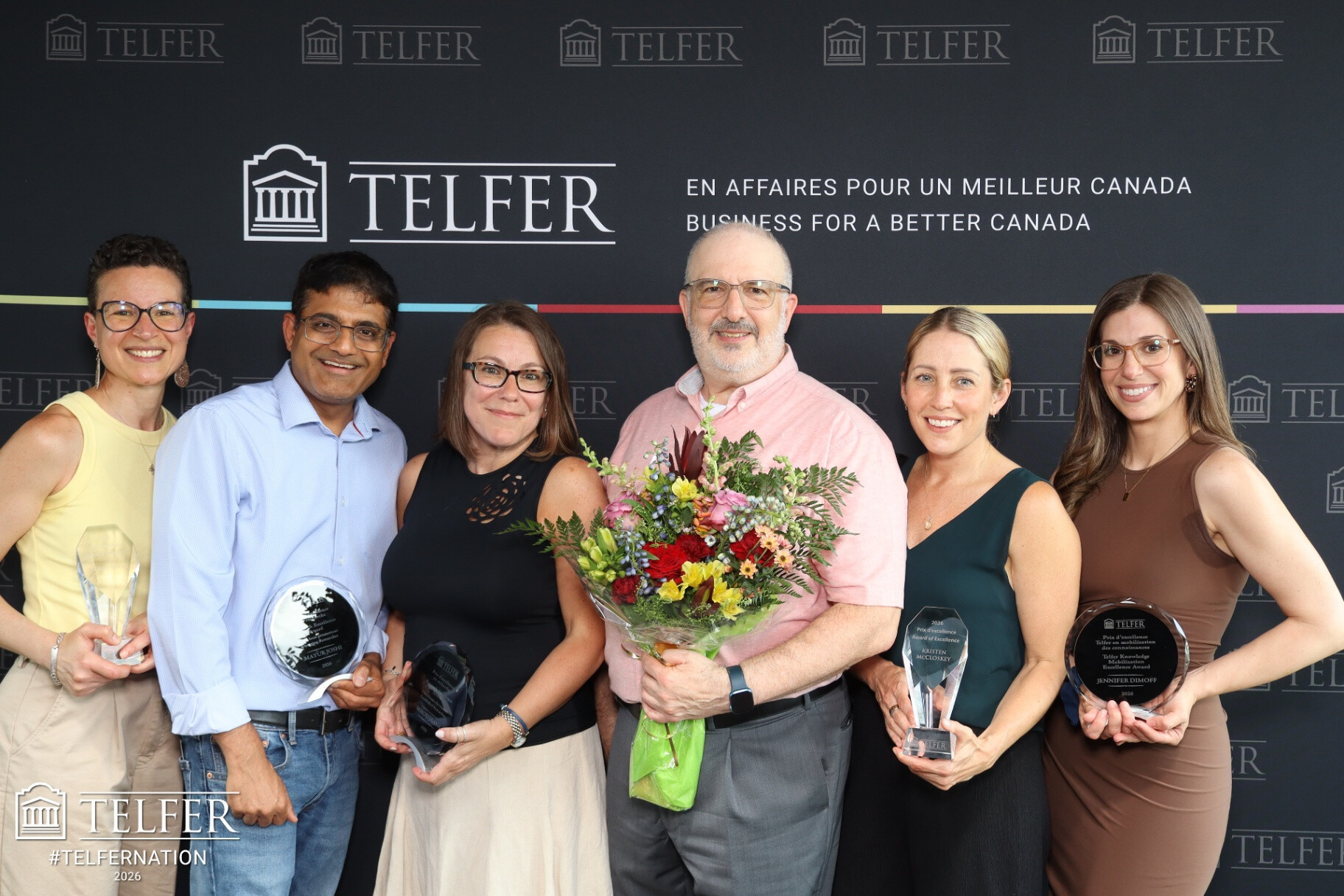 Des membres du personnel de l'École de gestion Telfer posent avec leurs prix devant une toile de fond lors de l'assemblée de l'École tenue en juin.