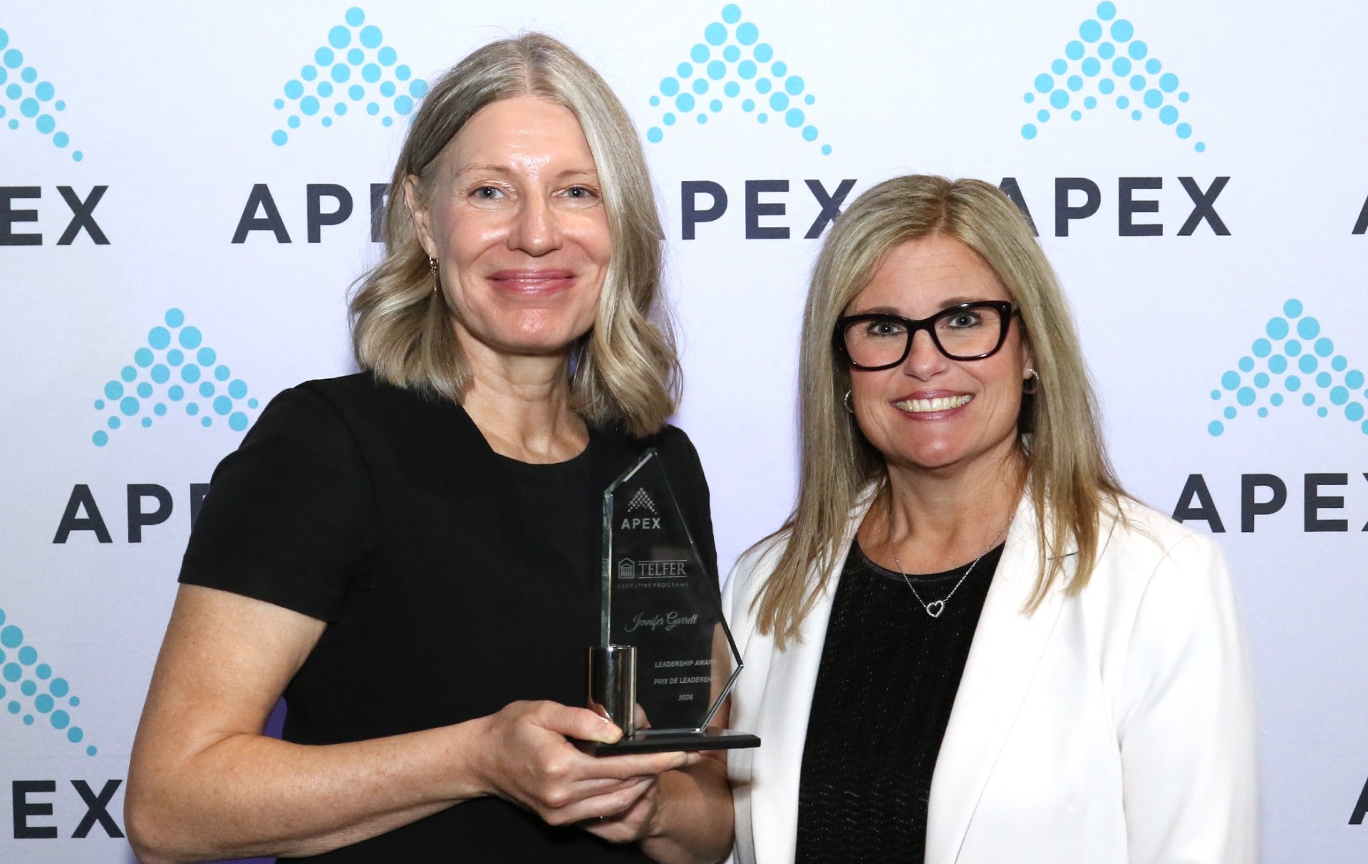 Jennifer Garrett tenant son prix de leadership à la cérémonie 2026 des prix d’excellence de l’APEX (Association professionnelle des cadres supérieurs de la fonction publique du Canada), aux côtés de Jennifer Gordon, directrice générale des Programmes pour cadres Telfer.