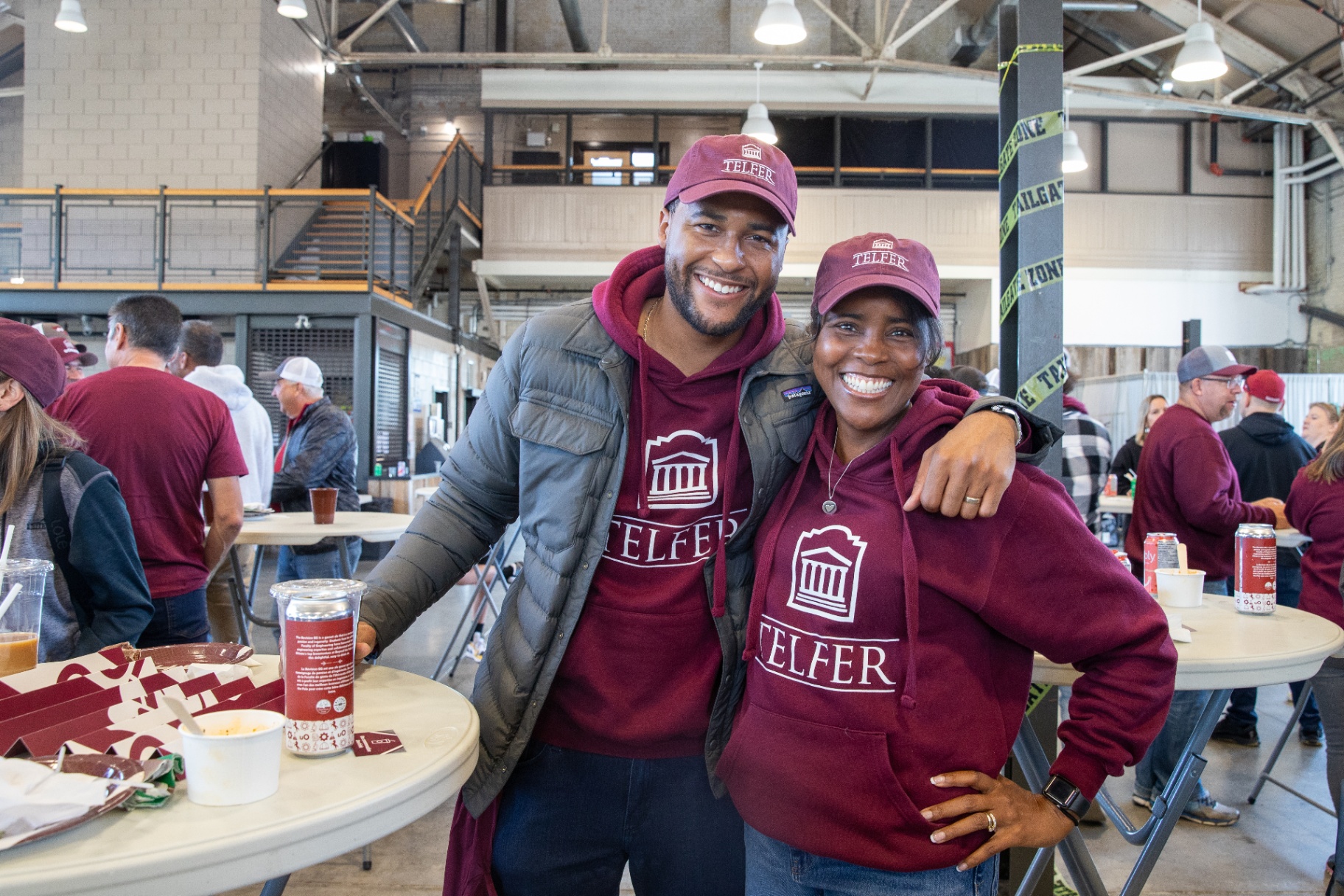 Tyson Rigg (left) poses with his arm around his mother (right) while both smile and wear matching Telfer hats and hoodies.