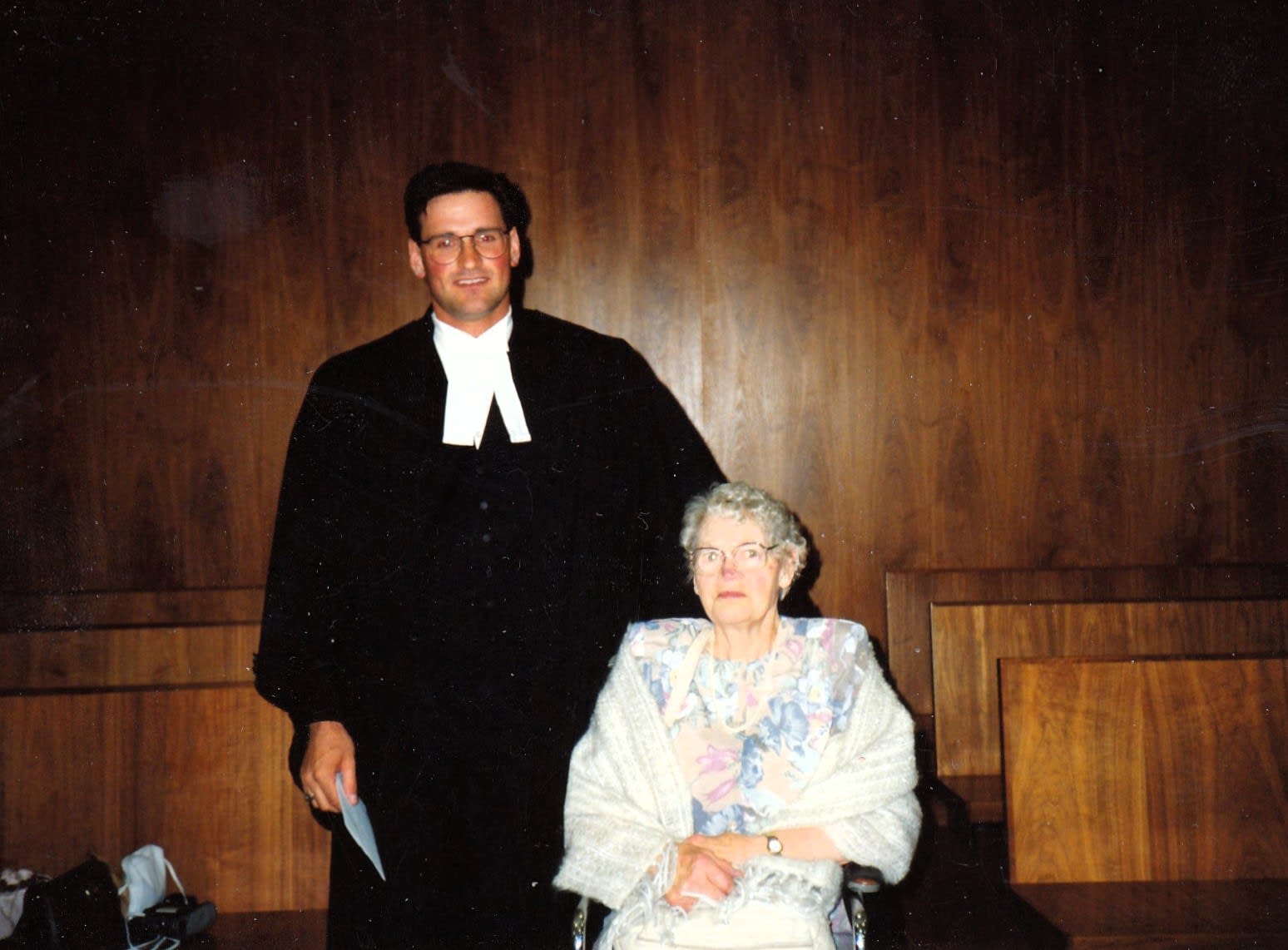 Myron Tetreault, dressed in black robe, stands next to an elderly woman.