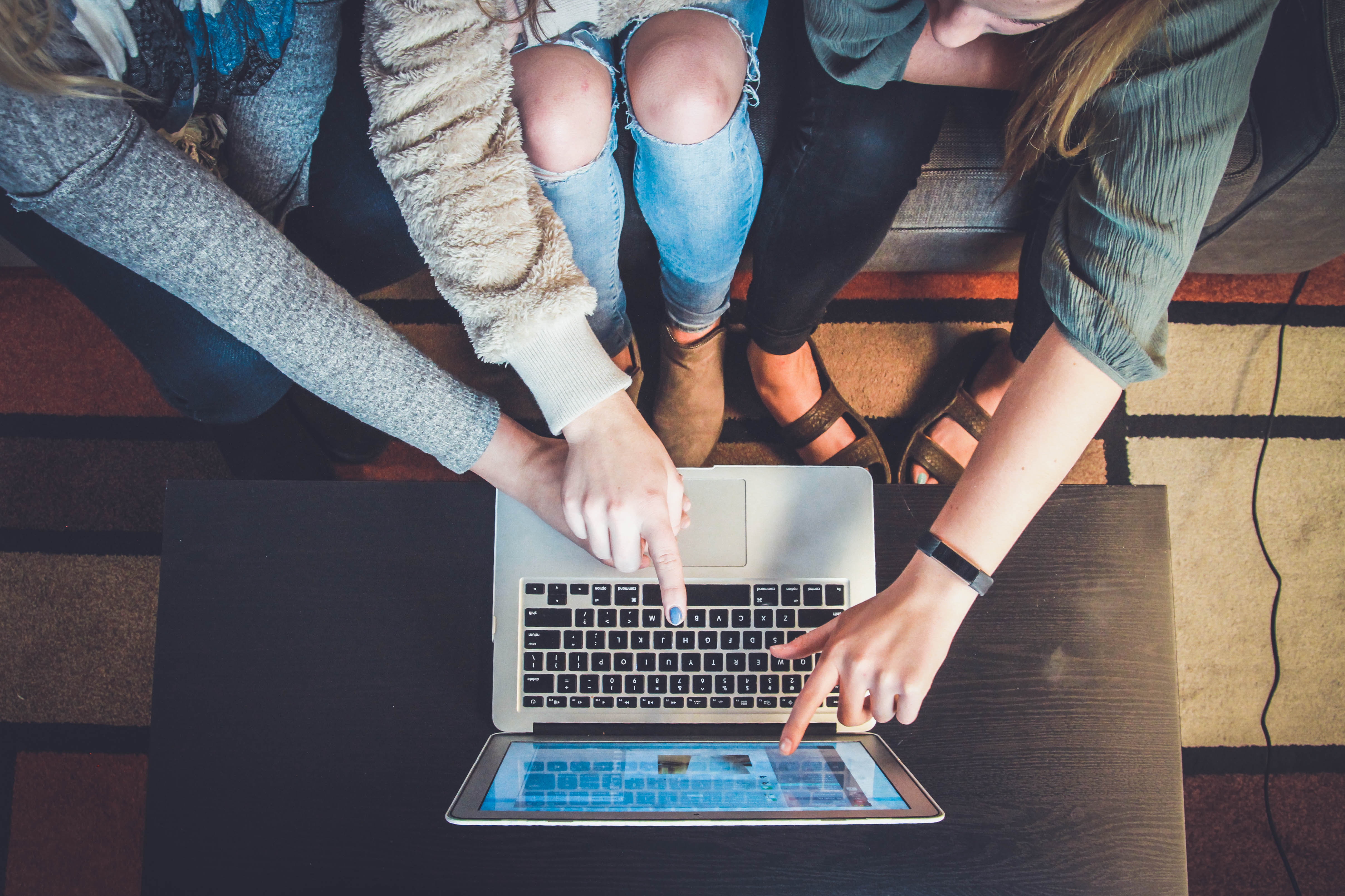 3 people pointing at a laptop in front of them