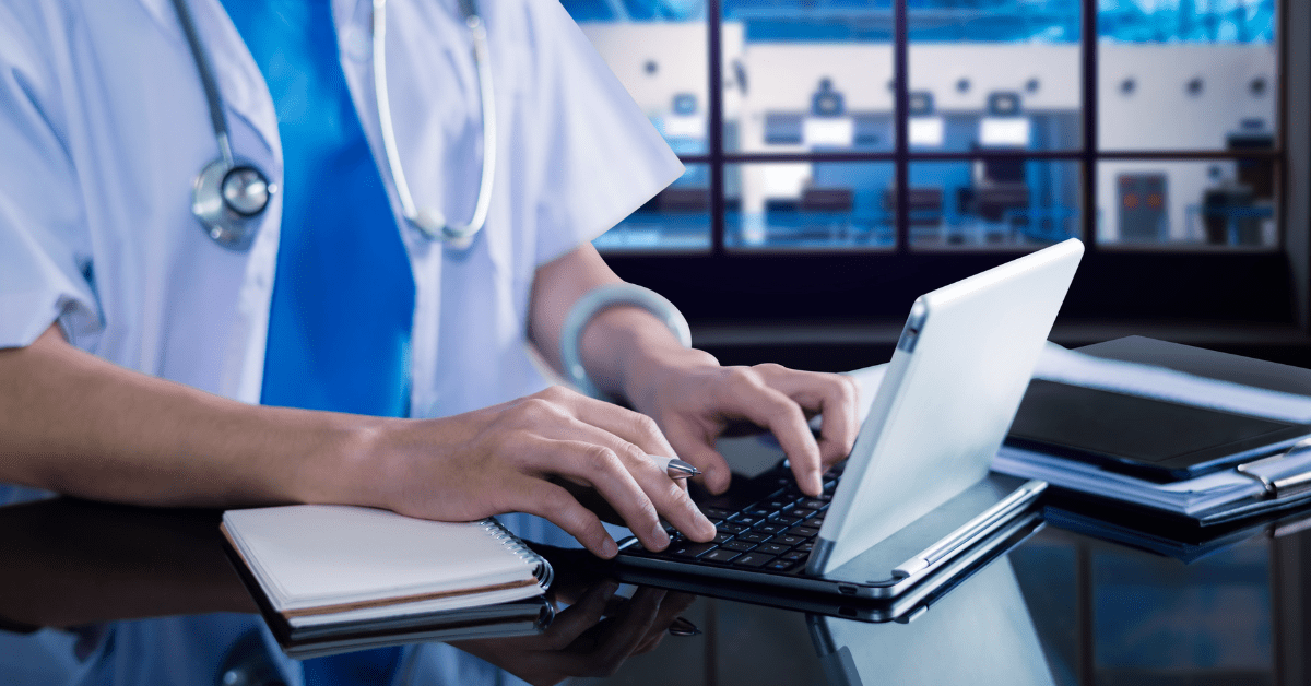 A doctor typing on a laptop