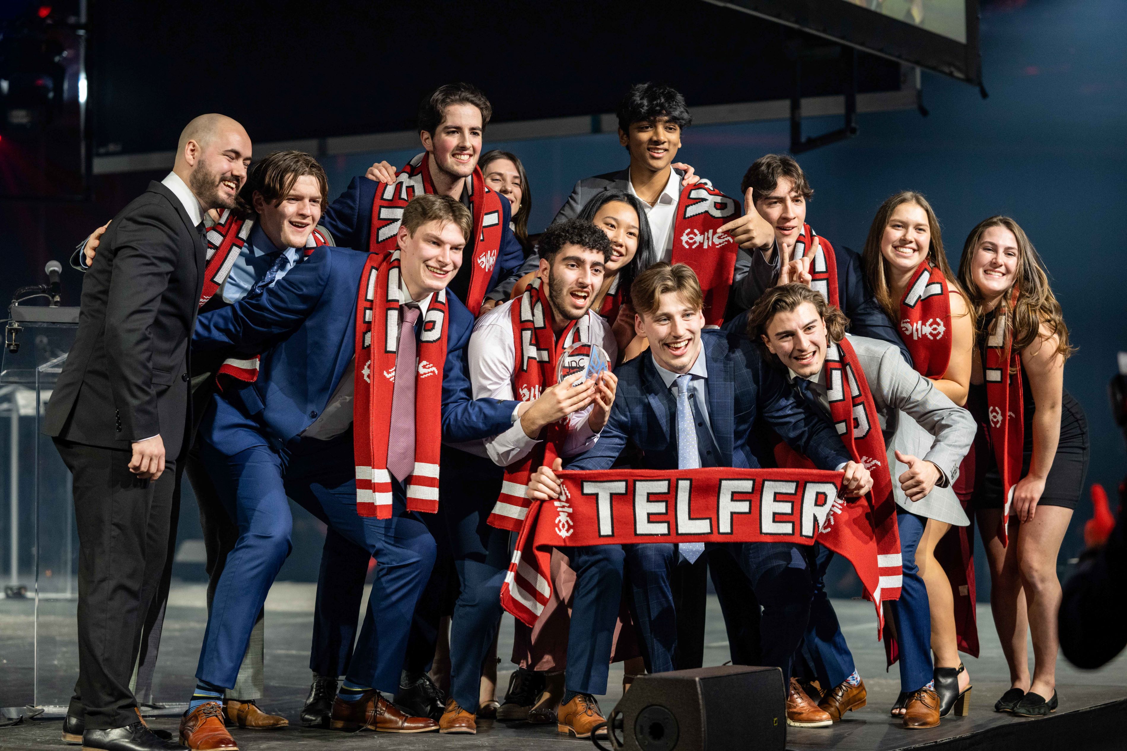 A group of students with “Telfer” scarves on stage accepting a prize.