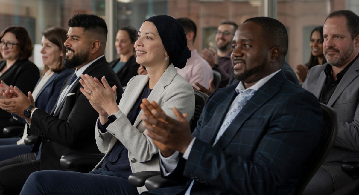 A group of Telfer Executive MBA alumni listening to a speaker and applauding