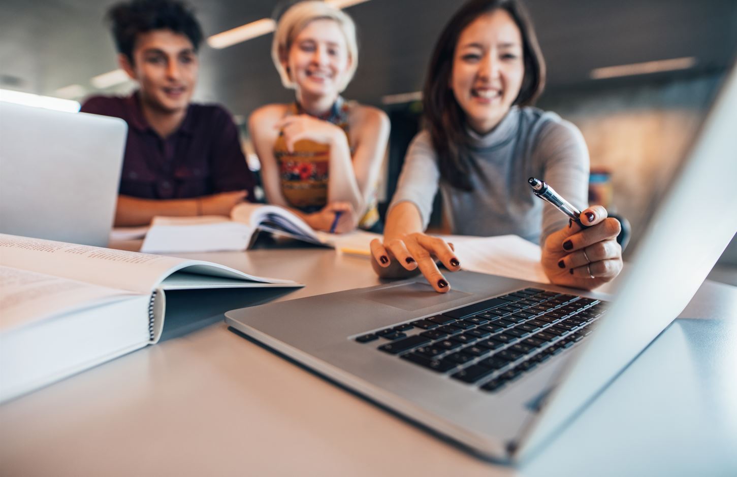 A group of three digital marketing students looking at a laptop.