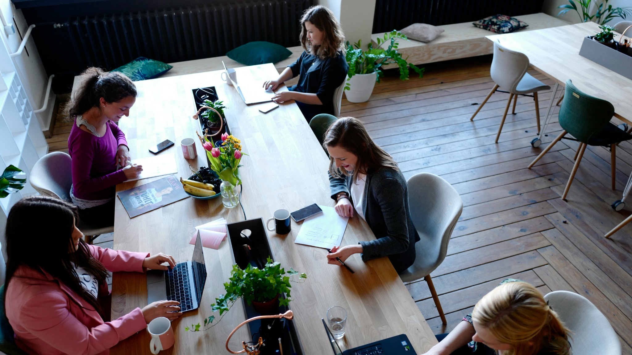 A group of women sitting around a wooden table while working