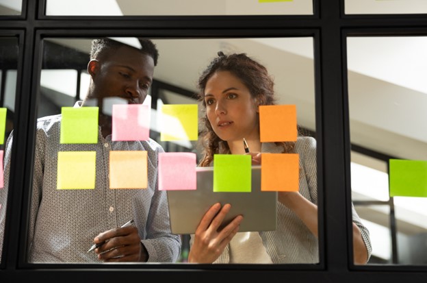 A man and a woman work at a Kanban board.
