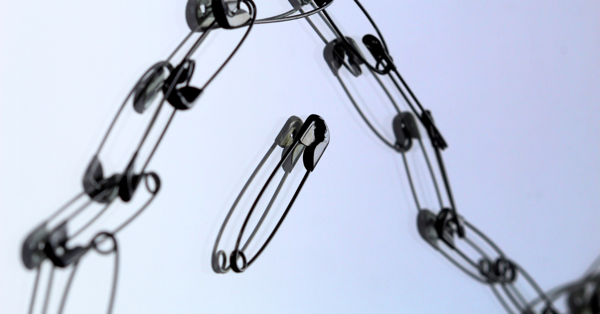A single safety pin in the center, disconnected from a chain of connected safety pins