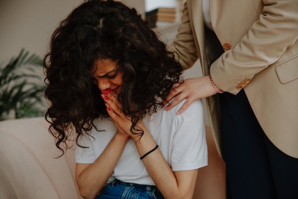 A woman crying and another person supporting her