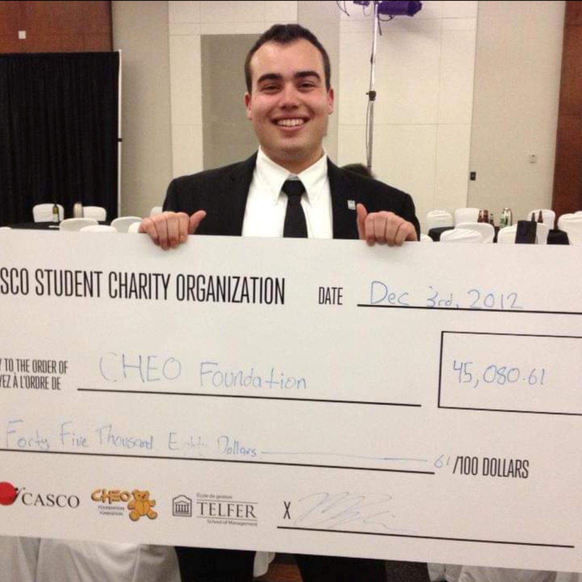 Adam Tomaszewski holding a large CASCO cheque