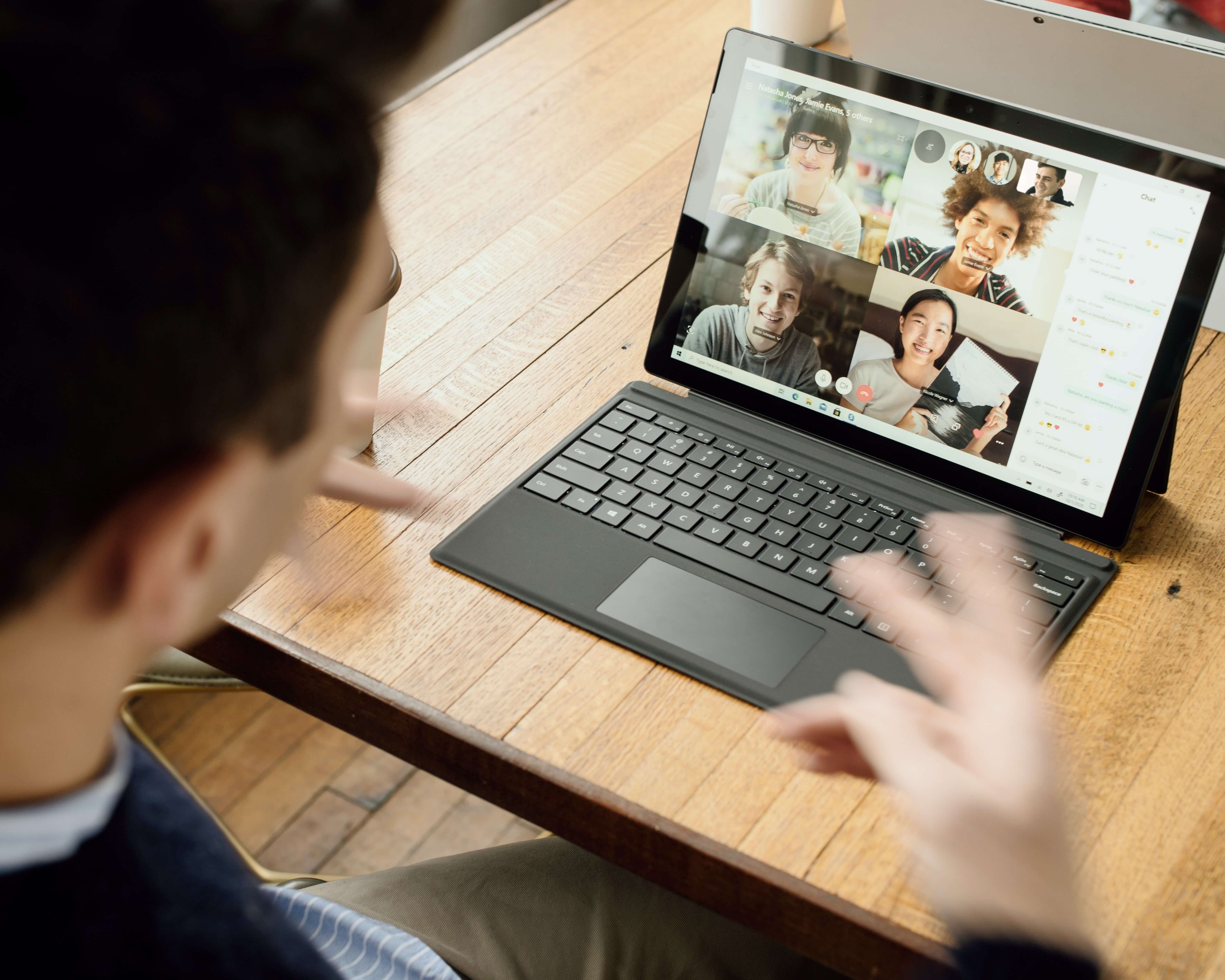 An MBA student having an online video call with coworkers on a laptop 