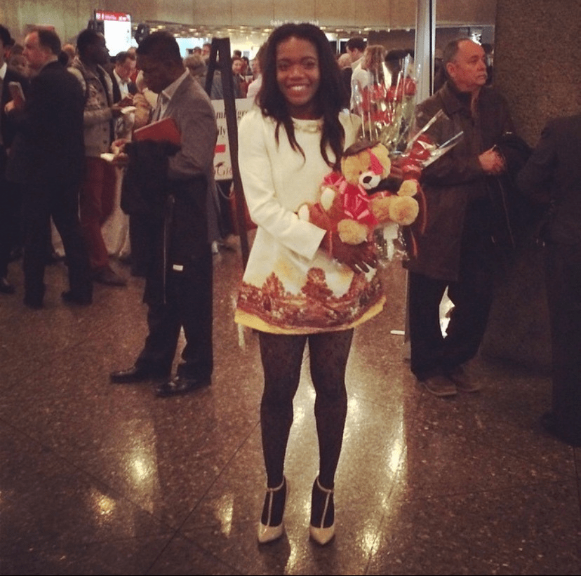 Chizoba tenant un bouquet de fleurs et un ours en peluche.