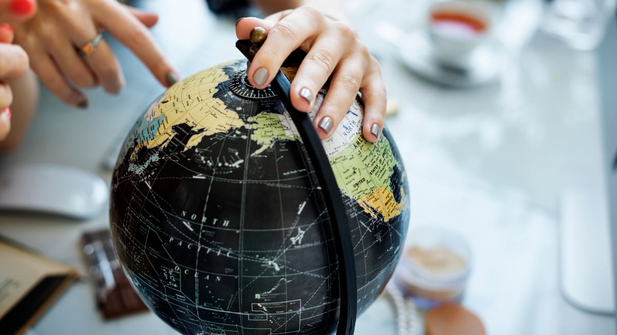 A person pointing a globe