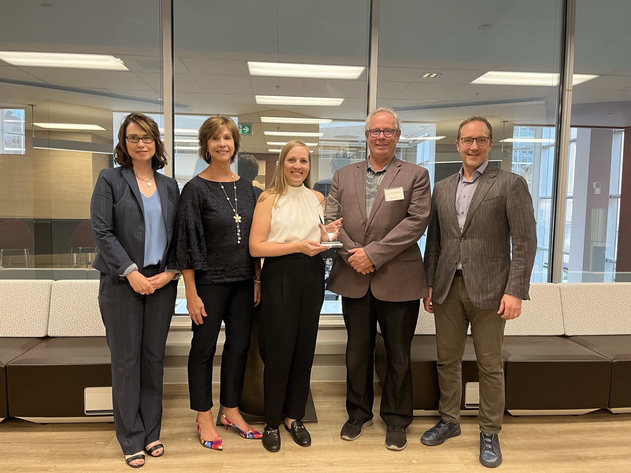 Dr. Jennifer McDonald holds her award alongside Samantha Hamilton, Mary Yates, Dr. Shaun McGuire, and Dr. Alan Forster at the Telfer Centre for Executive Leadership.