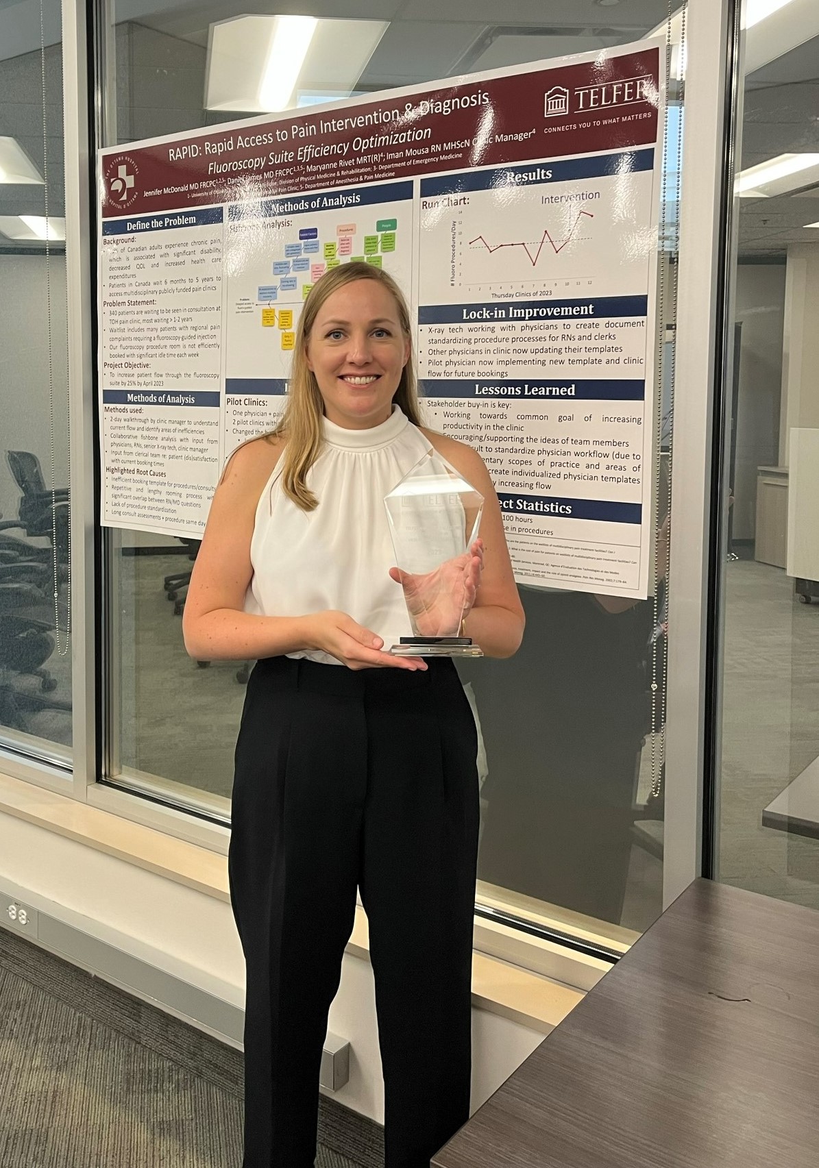 Dr. Jennifer McDonald stands in front of her project poster holding the 2023 Telfer Award of Excellence at the Telfer Centre for Executive Leadership.