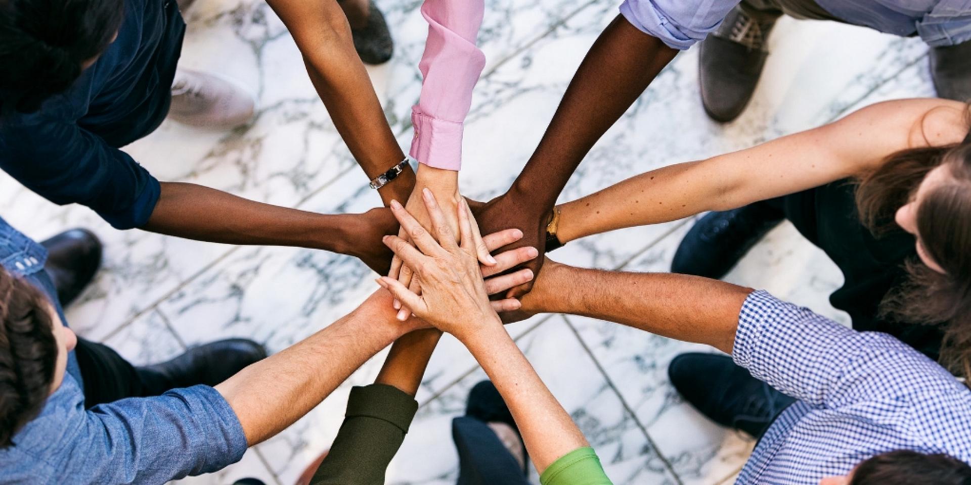 Group of people putting their hands all together in a the middle of a circle