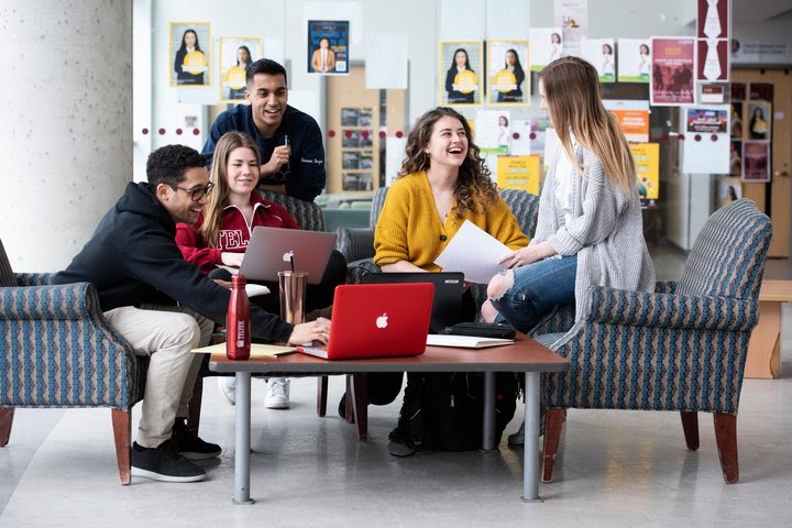 Group of Telfer students talking and studying together on couches in the student lounge at Desmarais building