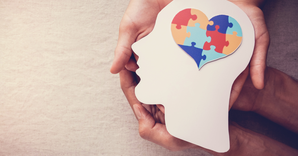Hands holding an outline of a head with puzzle piece heart inside