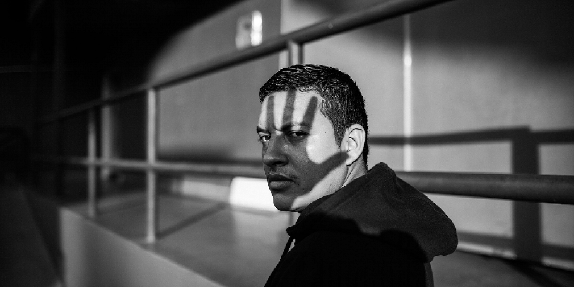 Homme debout dans l'obscurité avec l'ombre d'une main sur le visage.