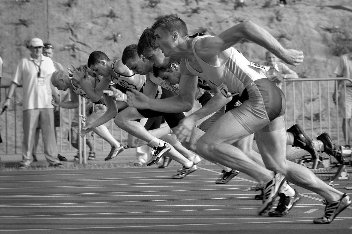 Black and white image of sprinters dashing from the starting block